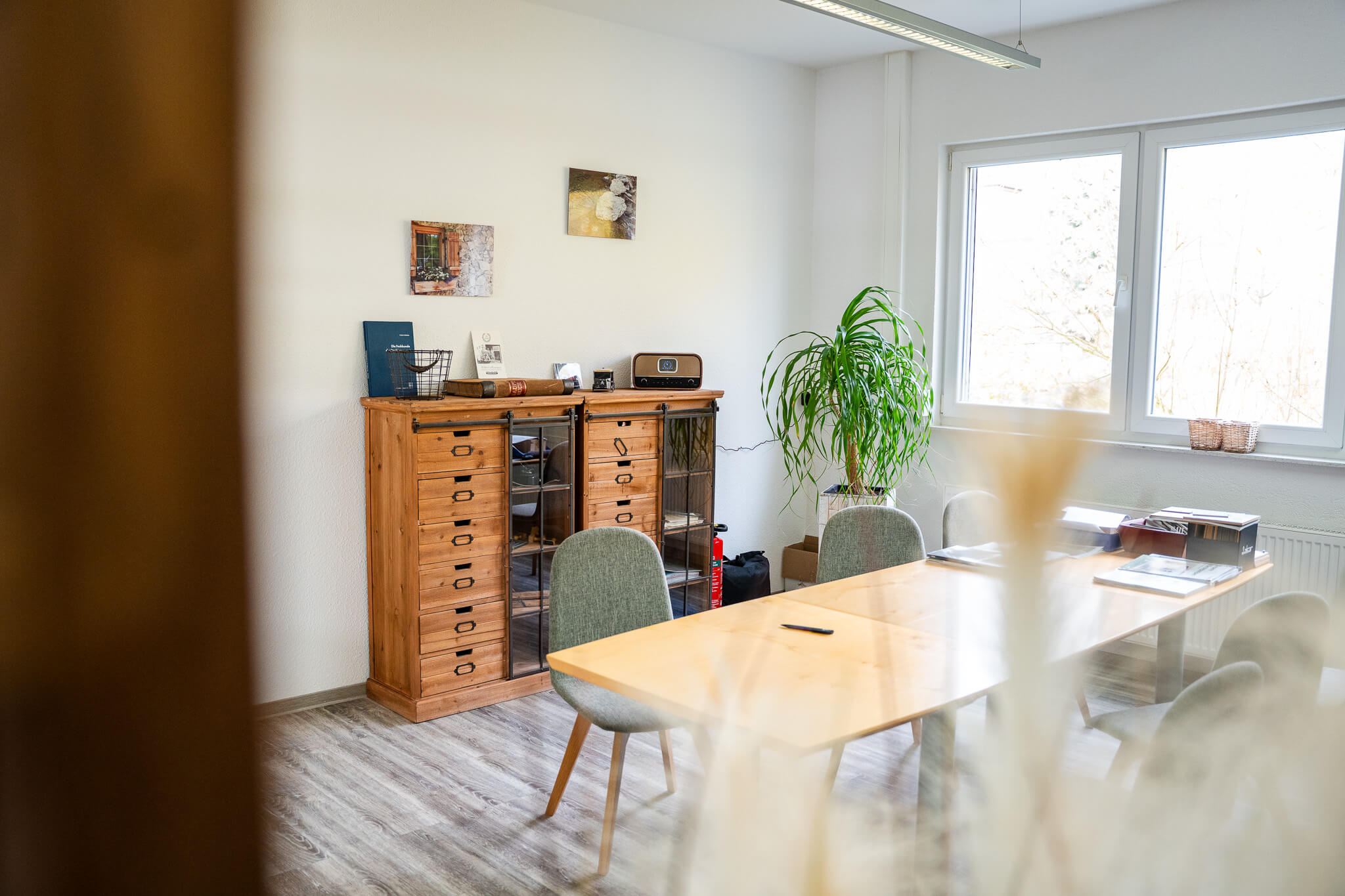 Heller Besprechungsraum mit modernem Holztisch, grünen Stühlen und großen Fenstern