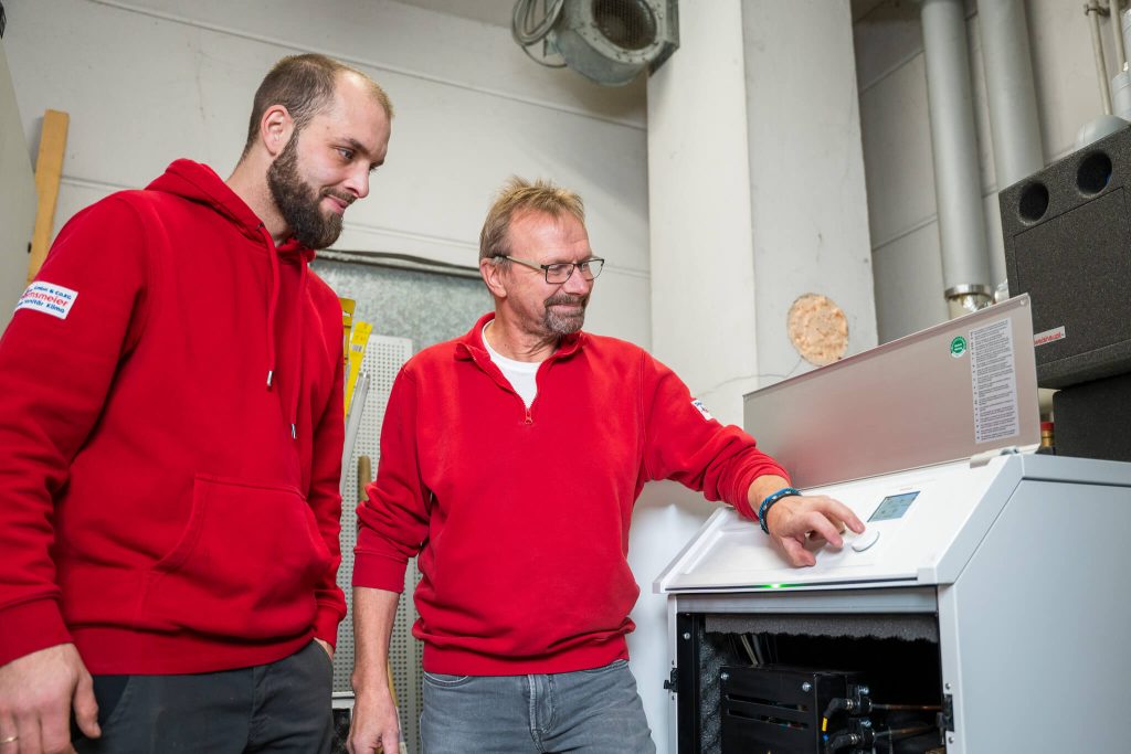 Zwei Heizungstechniker stellen gemeinsam moderne Heizungsanlage ein