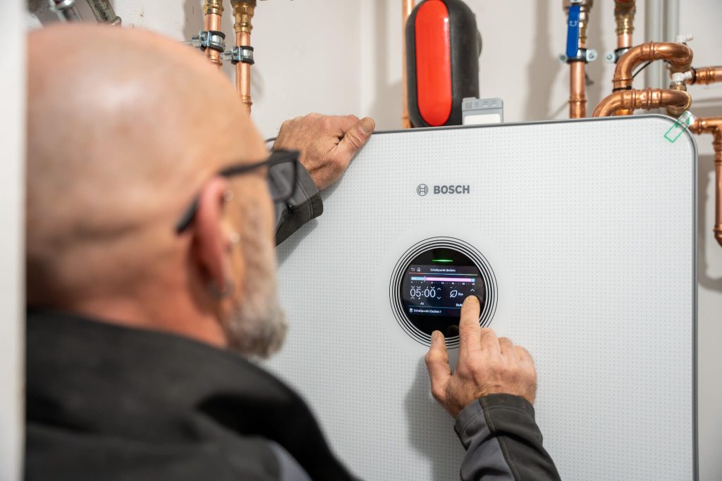 Techniker bedient digitales Touchscreen-Display an Bosch Wärmepumpe