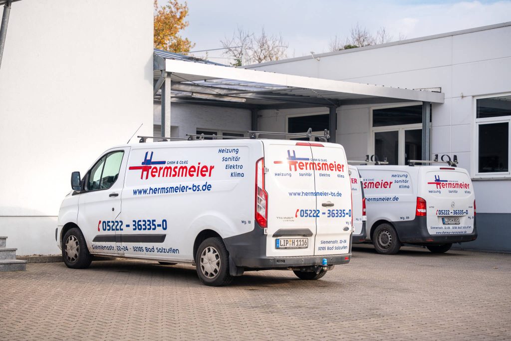 Drei weiße Servicefahrzeuge mit Hermsmeier-Beschriftung für Heizung, Sanitär, Elektro und Klima