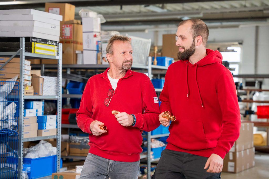 Zwei Techniker im Fachgespräch über Kupferfittings im Lagerhallen-Gang
