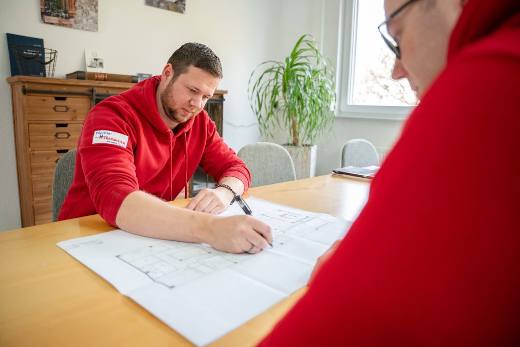 Zwei Fachkräfte besprechen Heizungs- und Sanitärinstallation anhand Bauplan